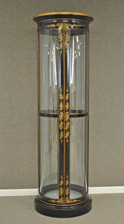 BLACK AND GOLD-PAINTED CURIO CABINET: in cylinder form, floral decoration, interior with five glass shelves, illuminated, height 81in., diameter of top 25in.