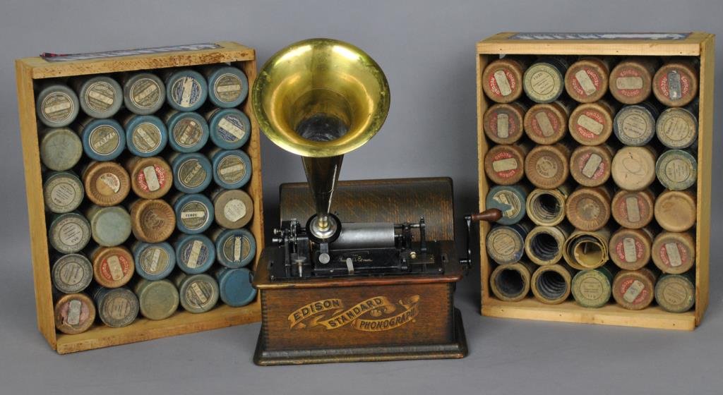 THOMAS EDISON 'STANDARD' PHONOGRAPH & CYLINDERS: phonograph with gold & black decal oak base, domed top, S/N S154076, brass horn, winds up and runs, lacks drive belt, together with 70+ cylinders