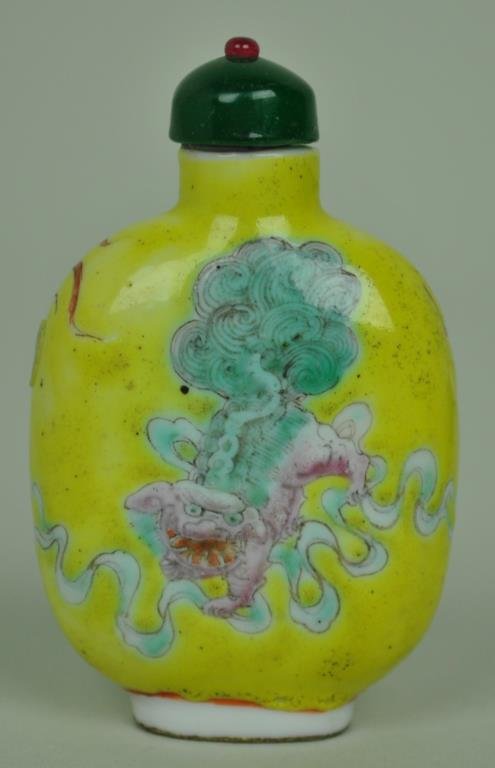 YELLOW-GROUND FAMILLE ROSE PORCELAIN SNUFF BOTTLE: Republic period or earlier, the body decorated on each side with a foo dog amongst clouds set against a lemon yellow ground, green and rose glass affixed stopper, 3in.