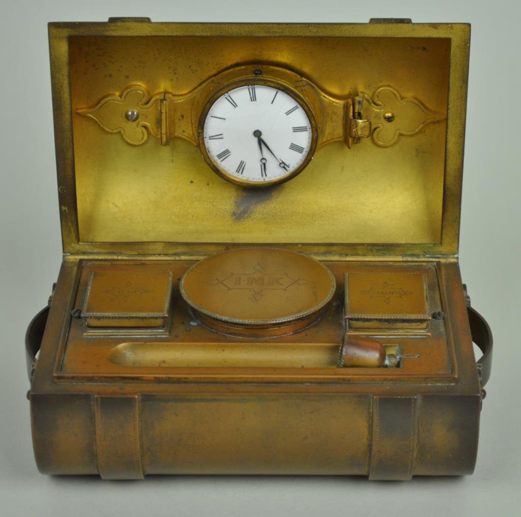 DECO BRONZE TRUNK-FORM TRAVELING DESK: case opening to 3 hinged compartments (lights, ink and stamps), and a swivel pen compartment (pen lacking), the domed top interior containing a key wind watch (no key), luggage straps ending with blue