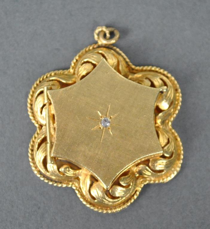 GOLD HINGED LOCKET PENDANT: set with a white center stone, in yellow gold, interior stamped 'Man Cast', verso stamped 14K, 1.5in., 13.9gms.