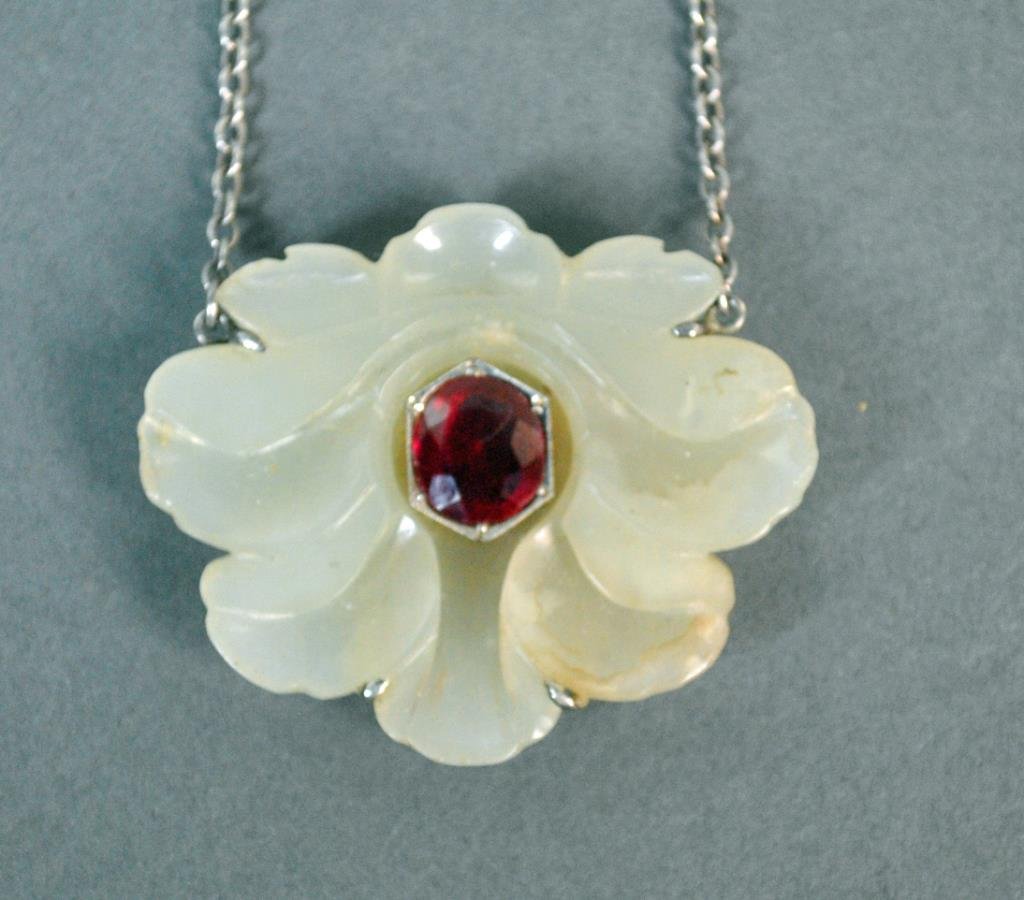 CARVED CHINESE WHITE JADE & RUBY LOTUS PENDANT: set with an oval ruby approx. 10x9mm, pendant 1.5x2in., on tested sterling mount and neckchain, 18in., pendant with edge flake / roughness, stone scratch, verso with adhesive residue at mounting point