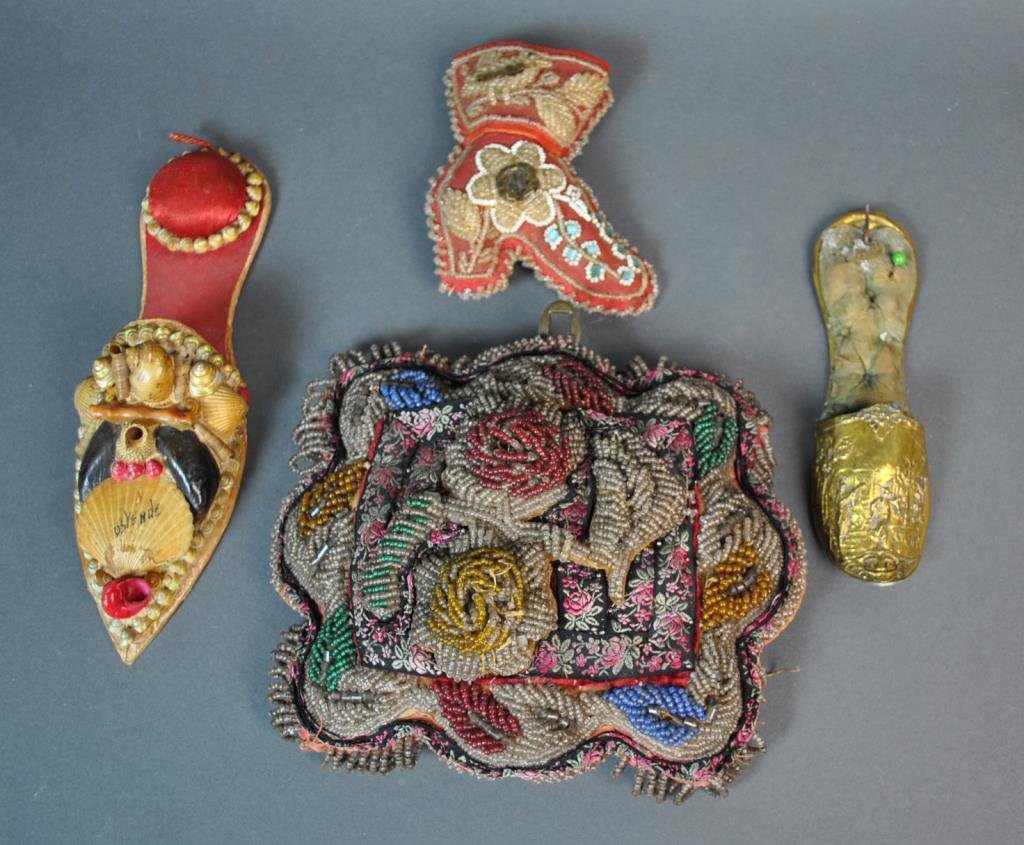 (4) VINTAGE PIN CUSHIONS: including a Victorian pillow form with rose fabric and glass beads, a glass beaded boot type, a shell art shoe-form example, and an Asian themed brass variety, largest 8x7in.