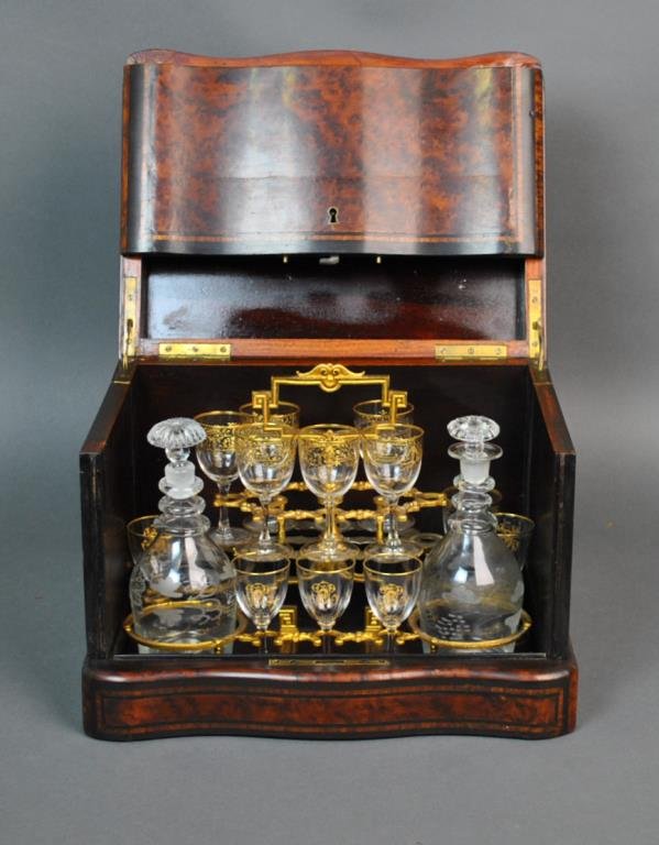 FRENCH (19THC.) BURLED WALNUT TANTALUS: with ebony inlay and trim, the case top with mother-of-pearl and brass inlay, swing out side panels, interior with lift out brass insert containing 2 grapevine etched bottles and 12 stems (7 stems etc