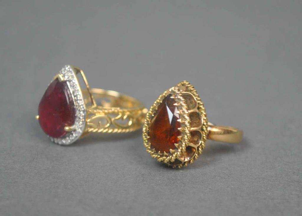 (2) GOLD PEAR SHAPE RINGS: one set with a red stone (likely ruby, inclusions) approx. 14x10mm, accented with melee (likely diamonds), stamped 10K India, size 6, the other set with a smoky topaz color stone approx. 12x8mm, stamp