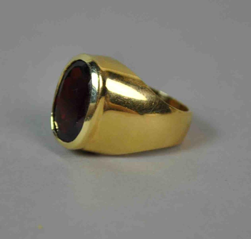 GENT'S GARNET RING: set with an oval faceted garnet stone approx. 15x10mm(minor surface scratch), yellow gold setting stamped 14K, size 8.25, 14.5gms.