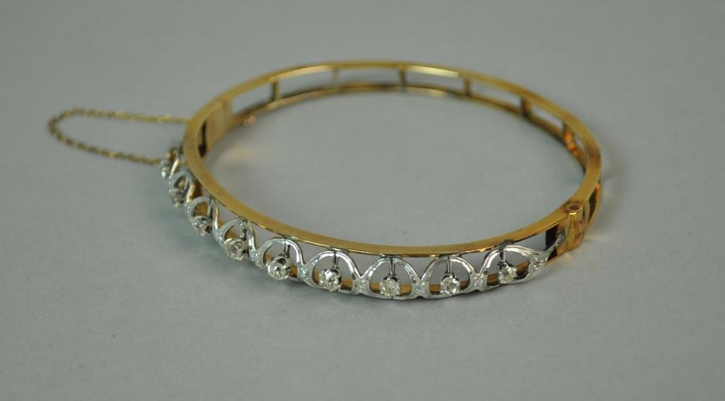 DIAMOND HINGED BANGLE, 1.00CTW: set with 19 round diamonds approx. 1.00 carats, yellow gold setting tests 14K, stamped 6060, safety chain, interior 2.5x2.25in., 13.8gms.