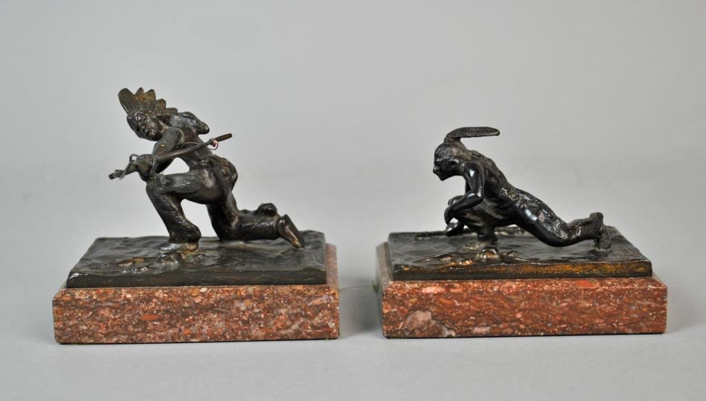 AFTER CARL KAUBA (Austrian / American, 1865-1922): two bronze American Indian figures, including one with a feather and rifle, and an as-is figure with headdress and bow / arrow (separation at shoulder), both signed C Kauba, marble bases, largest over