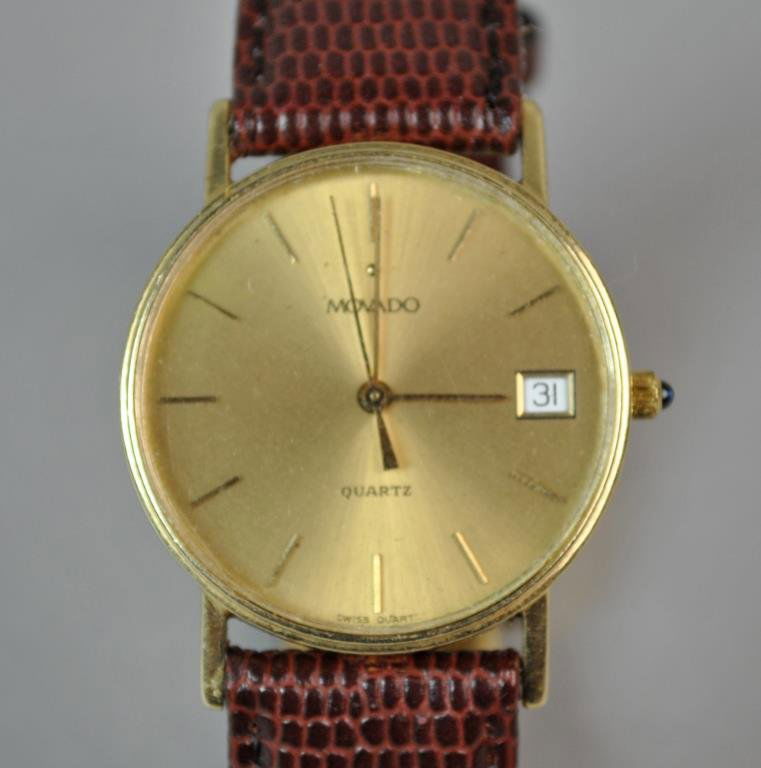 GENTS MOVADO GOLD CASE WATCH: ref: 7852885 / 80441, yellow gold case stamped 14K, sapphire crown, plated stainless and leather band, watch band 8.5in., non running, likely needs battery Note: watch band very tight fitting to lug p