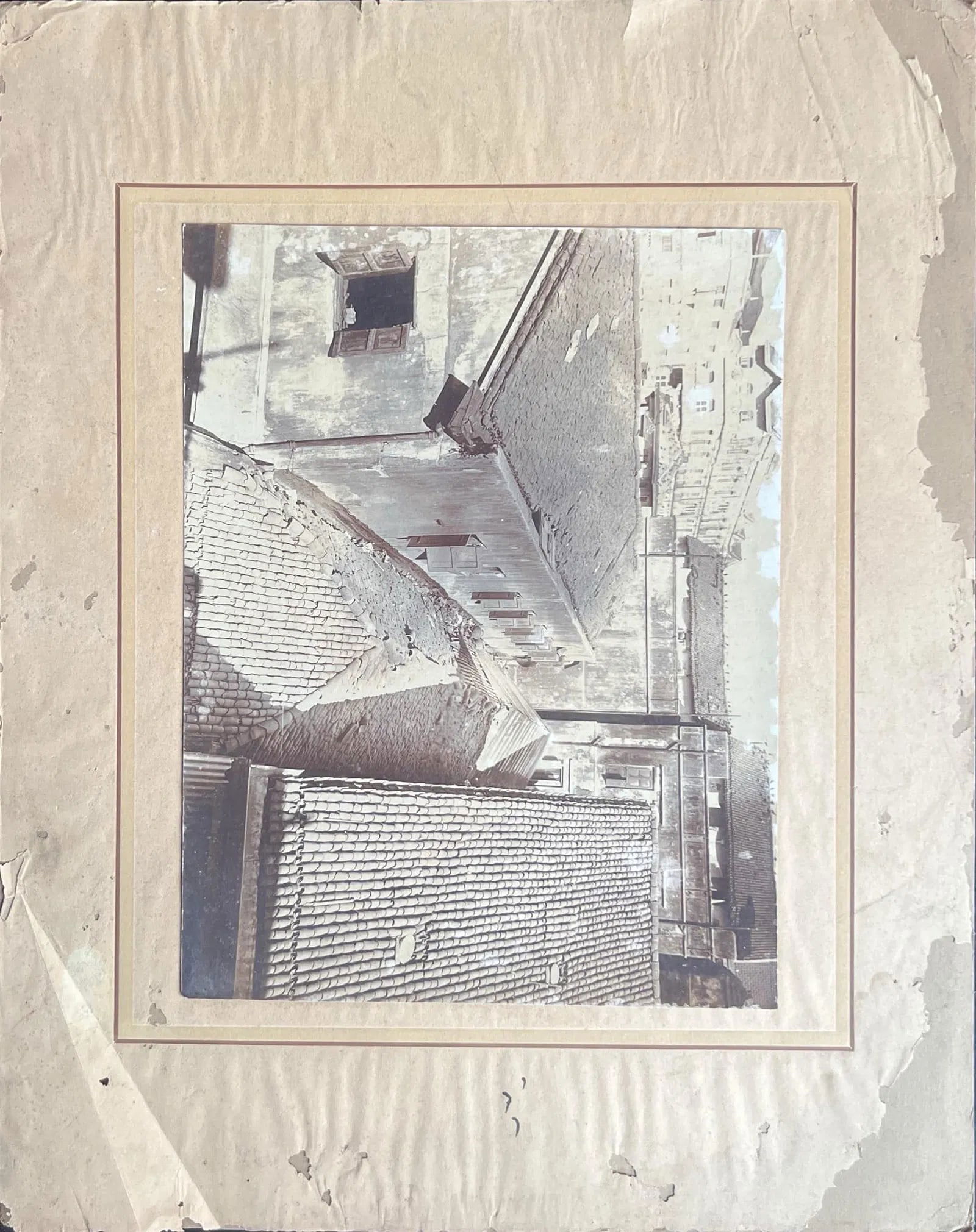 WEATHERED ROOFTOPS AND AGED COURTYARD WALLS: WEATHERED ROOFTOPS AND AGED COURTYARD WALLS THE IMAGE SHOWS A SERIES OF OLD, TILED ROOFTOPS AND WORN PLASTERED WALLS, ALL DISPLAYING CLEAR SIGNS OF AGE AND DETERIORATION. THE ROOFS ARE MADE OF TRADITI