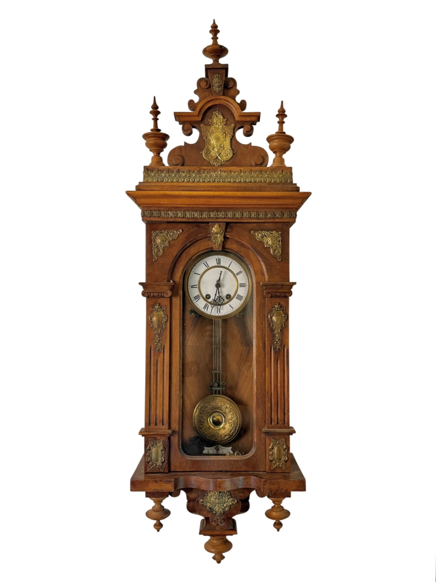 Wooden wall clock with three finials, bronze shield and face on the pediment. Ornate bronze applique: Wooden wall clock with three finials, bronze shield and face on the pediment. Ornate bronze applique on the case with a bronze face of the north wind on the base.