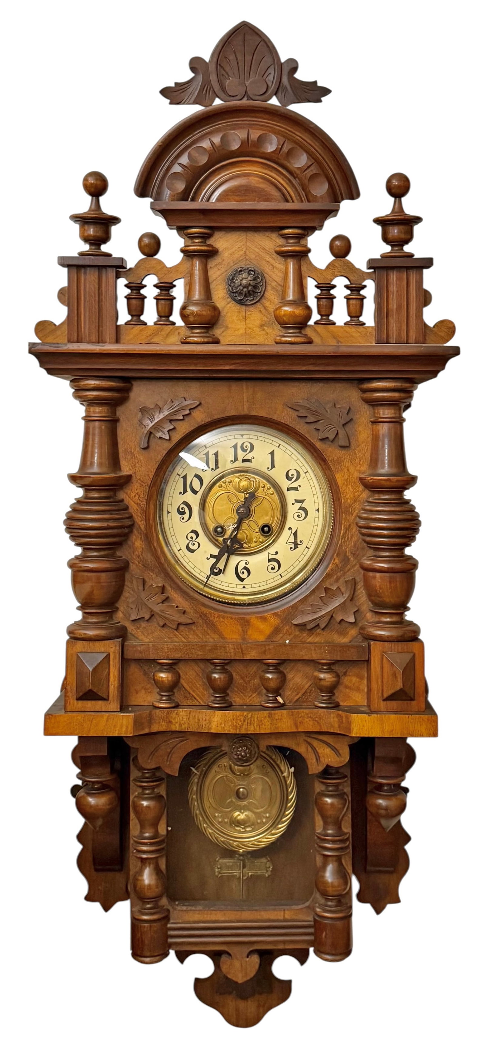 Wooden wall clock with closed well case Arched pediment two finals with an applique floral inset on: Wooden wall clock with closed well case Arched pediment two finals with an applique floral inset on the gallery. Two turned finals on the mid section of the case with floral and fruit motifs on the fa