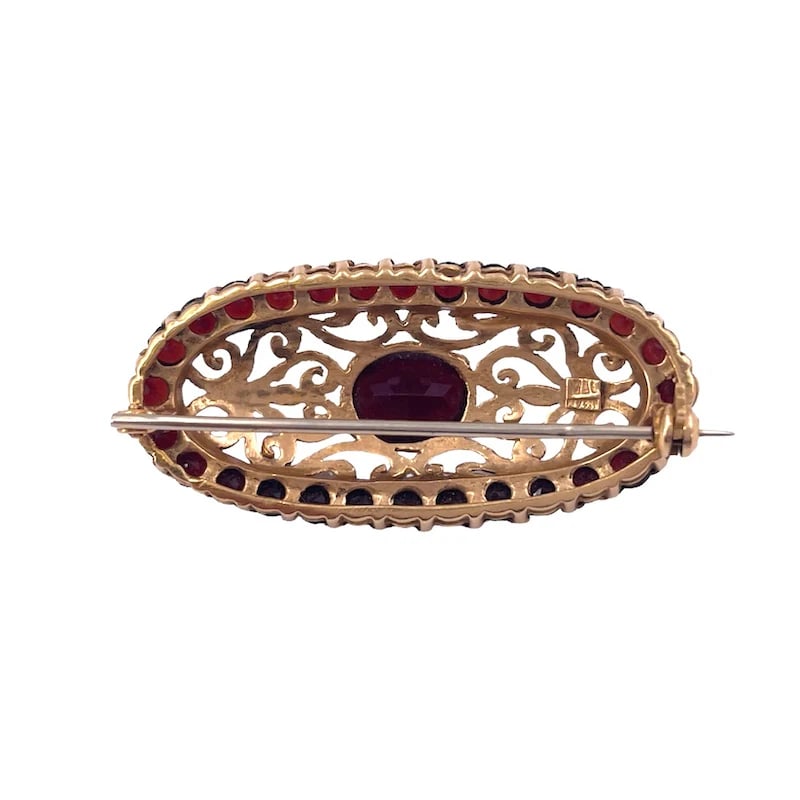 Vintage Oval Yellow Gold Brooch with Exquisite Garnets and Filigree Detailing, weight 10.39 g: A Captivating vintage oval brooch crafted in 18k yellow gold, featuring masterfully pierced filigree work and adorned with vibrant garnets. This miniature work of jewelry art combines refined