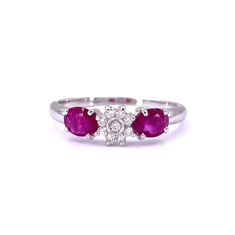 18k White Gold Ring with Two Rubies 0.89ct tot. and a Diamond Floral Accent 0.11 ct - weight 2.20 gr: A refined 18k white gold ring adorned with a delicate central floral accent of brilliant diamonds, complemented by elegant oval-cut rubies on the sides. Weight: 2.20 gr Ring Size: US 7.5 Frontal ring