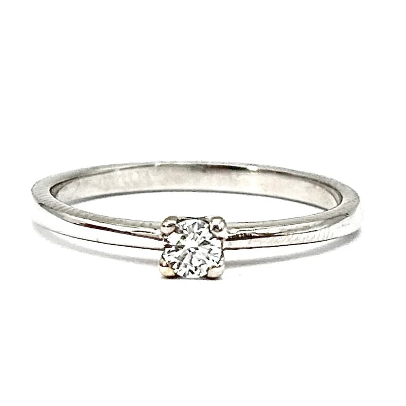 Graceful 18K White Gold Classic Center-Stone Ring with 0.14ct Diamond, Weight 2.31 gr: Graceful classic center-stone ring crafted in 18K white gold, featuring a brilliant-cut diamond that radiates timeless charm and refined sophistication. Designed for enduring elegance, this ring