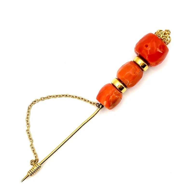 Retro Style Yellow Gold 18k Brooch with Natural Mediterranean Coral and Safety Chain, 7.70 gr: Retro Style 18k yellow gold brooch featuring a natural Mediterranean coral in its unique, imperfect form, enhanced with a safety chain for secure wear. A Stylish piece that radiates classic sophistica