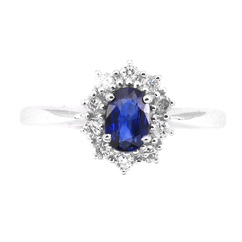 A 0.59ct Sapphire is set on this classic 18k White Gold Ring with 0.20ct Diamonds , 2.09 gr: A classic 18k white gold ring where an oval-cut Sapphire is set on a gold band and surrounded by brilliant diamonds, forming a refined floral motif. A classic design in a vibrant red variation, create