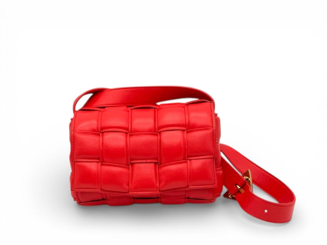 Bottega Veneta Padded Cassette Red Leather - Iconic & Bold: The revolutionary Bottega Veneta Padded Cassette, a modern icon of the Maison featuring the bold, oversized "Intrecciato" weave. Crafted from luxurious red leather with striking gold hardware, this pi