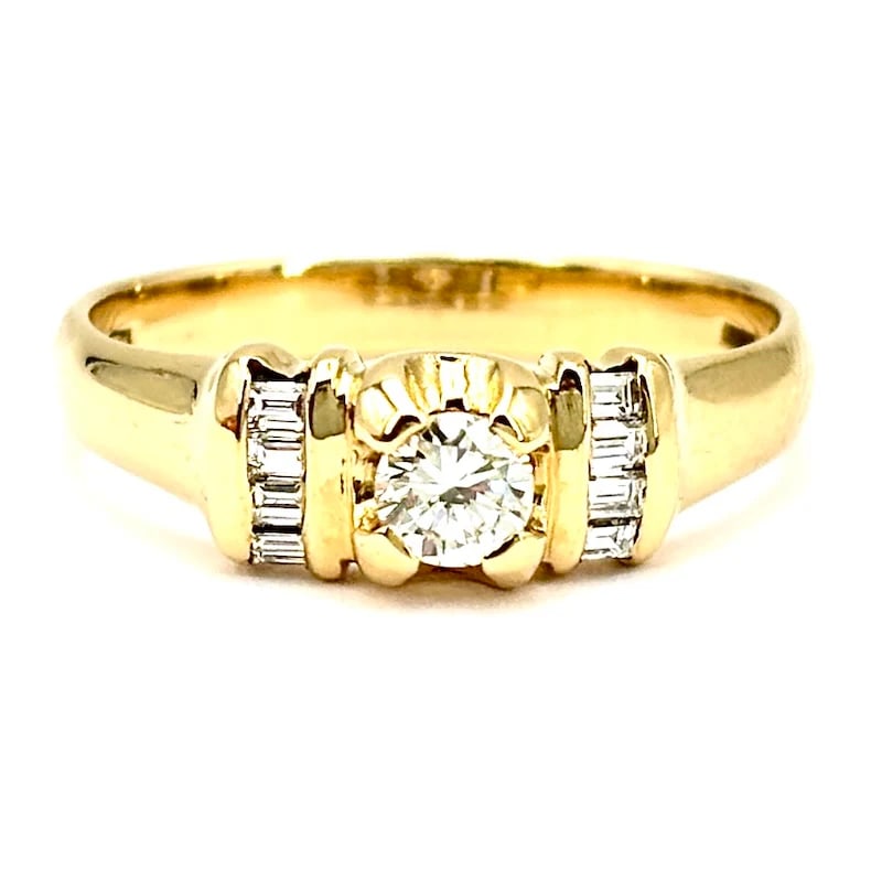 Elegant 18kt Yellow Gold Band Ring with 0.19ct Brilliant Diamond and Baguette Accents 0.34ct total -: Elegant 18kt yellow gold band ring featuring a sparkling brilliant-cut solitaire diamond complemented by sleek baguette diamond accents along the sides. A charming, luxurious piece designed for comfor