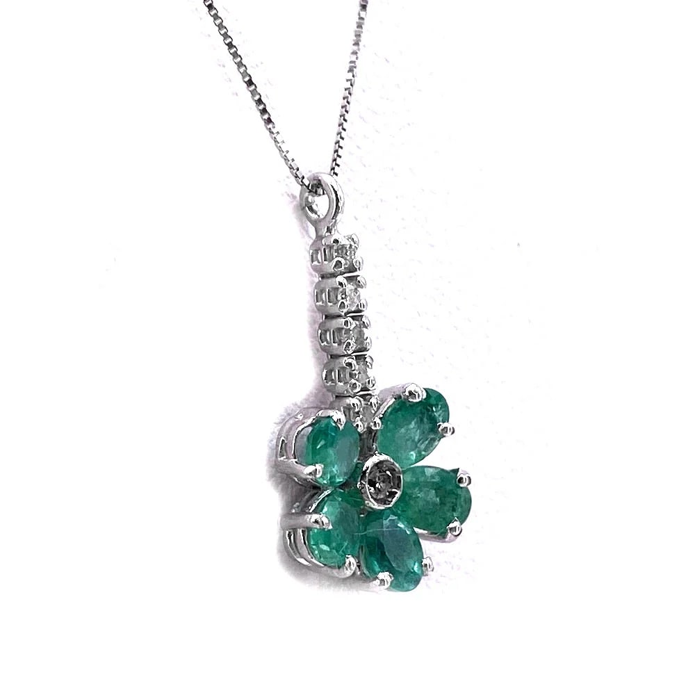 0.09ct Emeralds on this Flower Pendant full of 0.05ct Diamonds on 18kt White Gold Box Chain - 1.89gr: Flower-inspired pendant in white gold 18kt featuring polished emerald petals and a tiny diamond spark accent. Comes with a refined white gold 18kt box. A delicate and stylish piece adding color and so