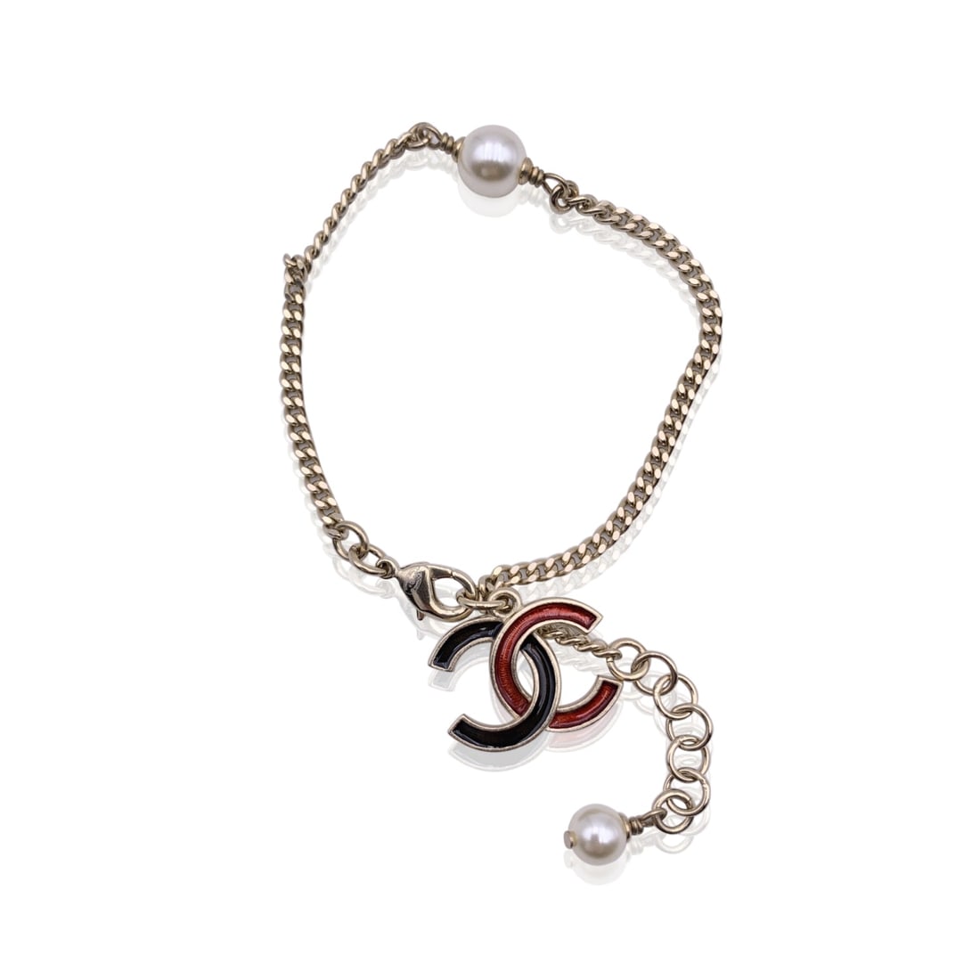 Chanel Metal Bracelet CC: Delicate yet unmistakably Chanel, this light gold metal chain bracelet captures the house's playful elegance. A black-and-red enameled CC charm swings gracefully from the fine links, while two petite