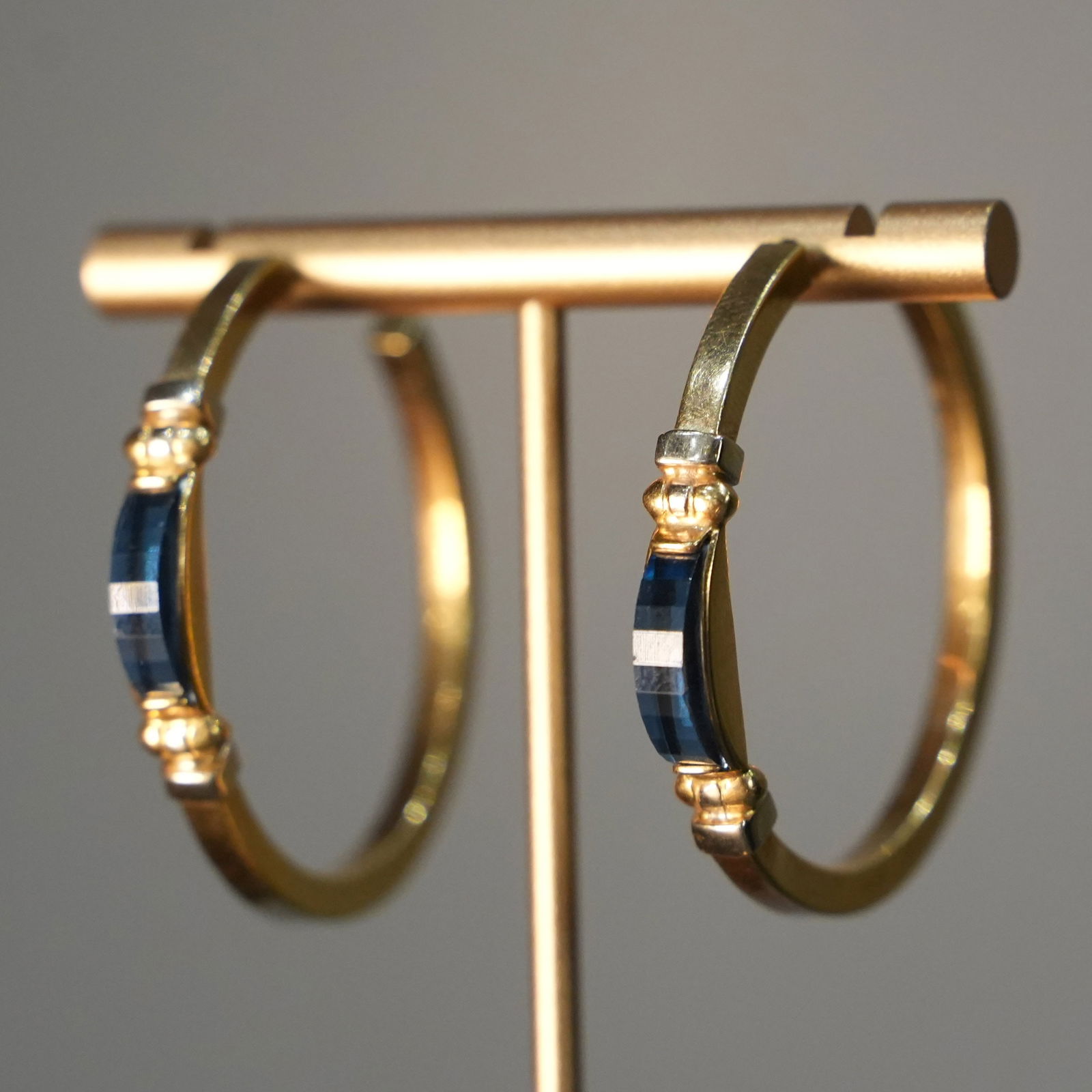 18K Yellow Gold Hoop Earrings with Post and Butterfly Closure Adorned with Two Blue Quartz, 12.20 gr: Classic 18K yellow gold hoop earrings featuring a post and butterfly closure accented by two vivid blue quartz stones. The quartz gems are set directly on the closure, adding a subtle yet striking tou