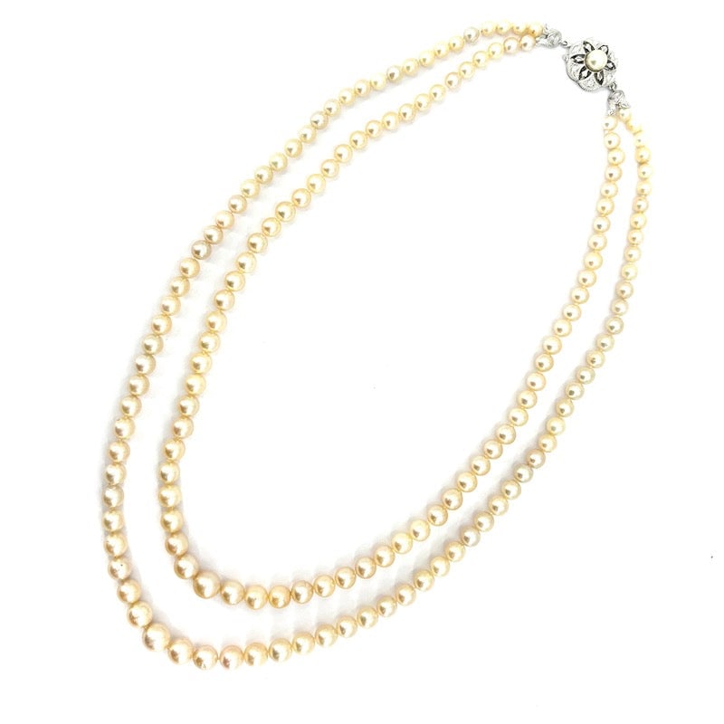 Double strand pearl necklace, gold style flower clasp, pearl and diamonds; 56.72 g - 48 cm: Sophistication and class to the nth degree for this stunning two-strand necklace of scaled Japanese Akoya pearls, with adorable vintage flower clasp, in 18 kt white gold with diamonds and central pear