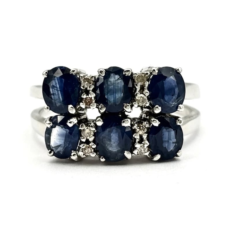 Striking 18K White Gold Double Trilogy Ring with 1.50-2.00ct Sapphires, 0.06-0.08ct Diamonds, 4.75g: Striking double trilogy ring crafted in 18K white gold, featuring vivid blue sapphires paired with sparkling brilliant diamonds, offering a bold yet refined look. Pre-owned in excellent condition with