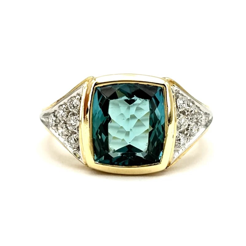 A Blue Topaz is on this Bold 18K Yellow Gold Fashion Design Ring with 0.25-0.30ct Diamonds, 7.85g: Bold fashion ring in 18K yellow gold featuring a square-cut blue topaz with refined geometric lines, enhanced by sparkling side diamonds. A modern design with bright contrast, confident feminine chara