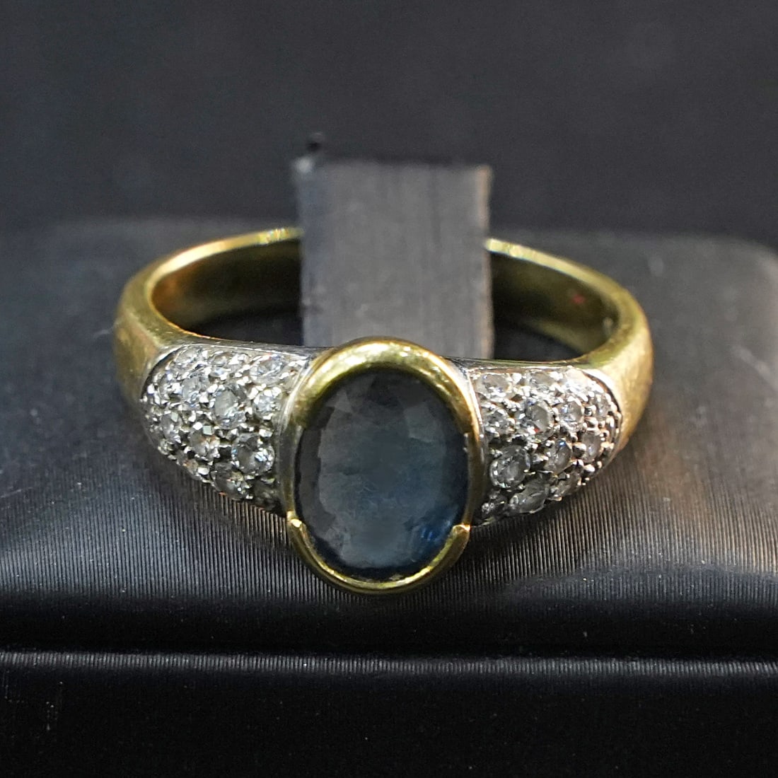 18K Yellow and White Gold Ring with Central Sapphire and two Side Diamond Clusters 5.40ct tot, 7.07g: Exquisite 18K yellow and white gold ring featuring a vibrant central sapphire flanked by two elegant clusters of diamonds, creating a dazzling contrast and sophisticated design. The dual diamond accen