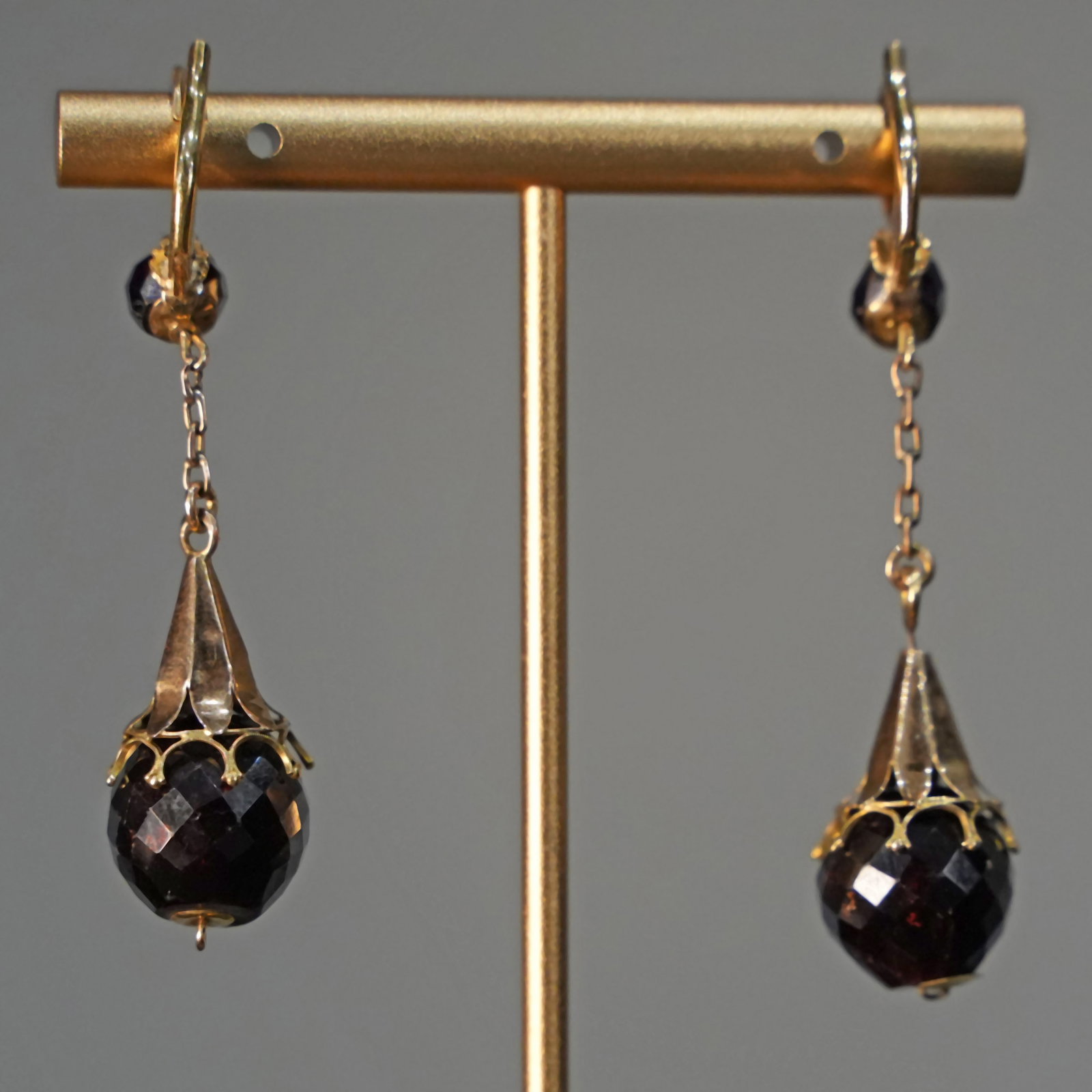 Classic 18K Yellow Gold Drop Earrings with Faceted Garnets on Delicate Chain, 12.16gr: Classic 18K yellow gold earrings featuring elegant drop design that sways gracefully with every movement. Suspended from fine classic-link chains, each earring showcases a sculpted element culminating