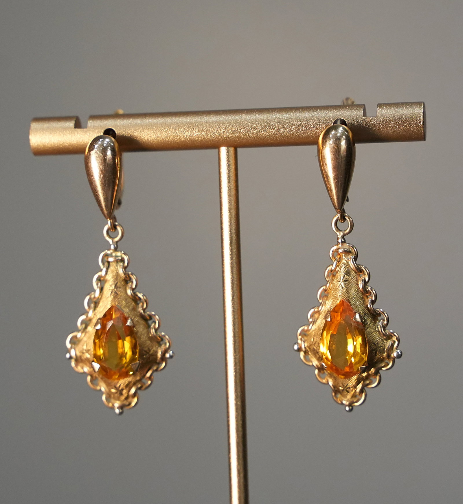 Elegant Retro Style 18K Yellow Gold Hook Drop Earrings with n. 2 Yellow Quartz, 6.96 gr: Elegant drop earrings crafted in solid 18K yellow gold, featuring a traditional leverback hook closure and a vintage-inspired aesthetic. The lozenge-shaped structure is defined by a softly scalloped e