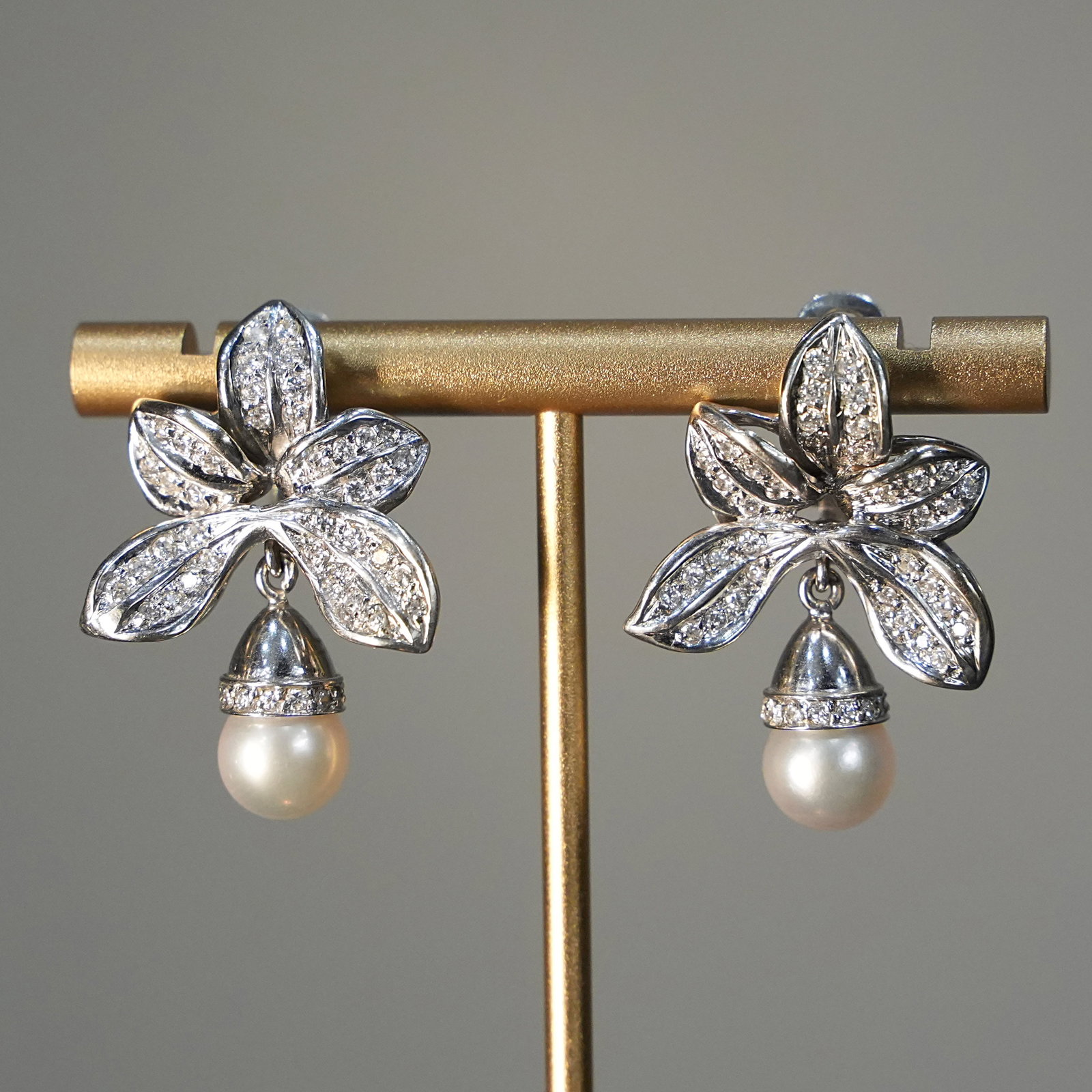 18K White Gold Flower Drop Clip Earrings with Diamond-Studded Petals and Pearls, 16.67 gr: Elegant white gold earrings crafted in 18K with a floral-inspired design, featuring petals fully diamond-studded for radiant sparkle. Each earring is enhanced by a delicate acorn-shaped drop ending wi