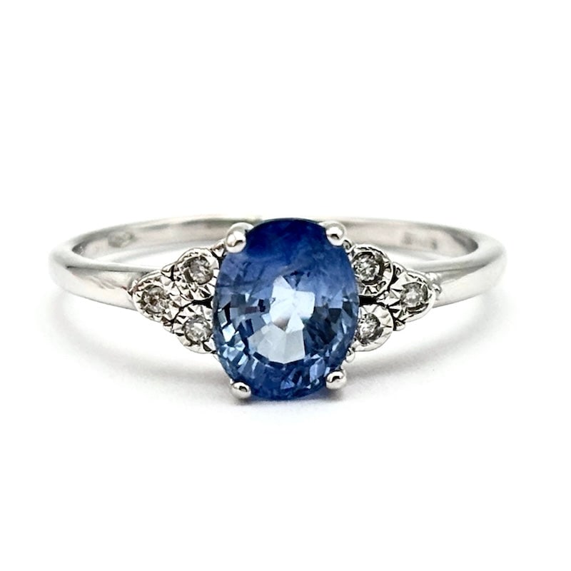 Sapphire and diamond triptych ring, white gold; 1.88 gr.: Adorable, romantic and precious bargain ring! 18 kt white gold ring with side triptychs of glitter and stunning central oval-cut sapphire. A most exquisite delight! Our company's certification is avai