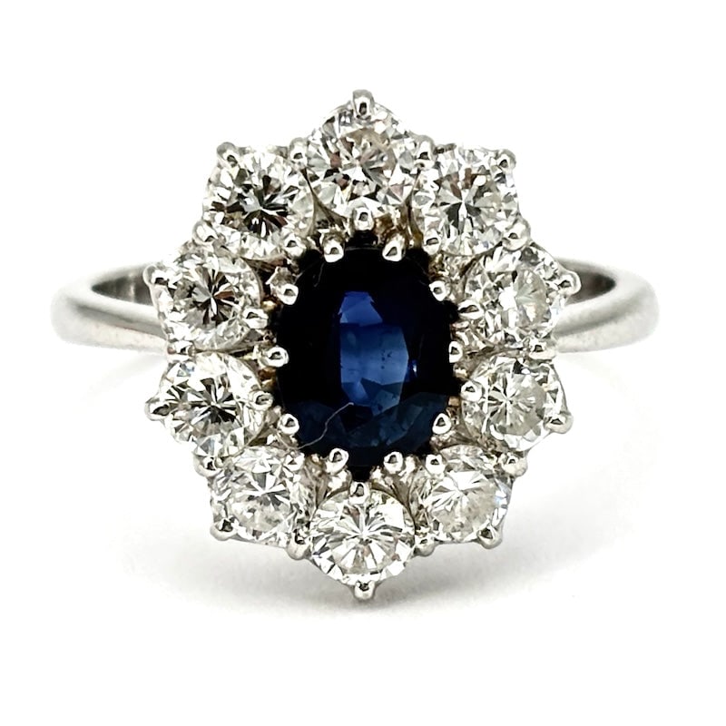 Daisy ring sapphire and brilliants OCCASION; 5.54 gr.: A timeless classic in blue and white variant of the highest jewelry! Daisy ring in white gold, with enchanting central oval-cut sapphire framed by fabulous, all-important brilliants. The must-have bar