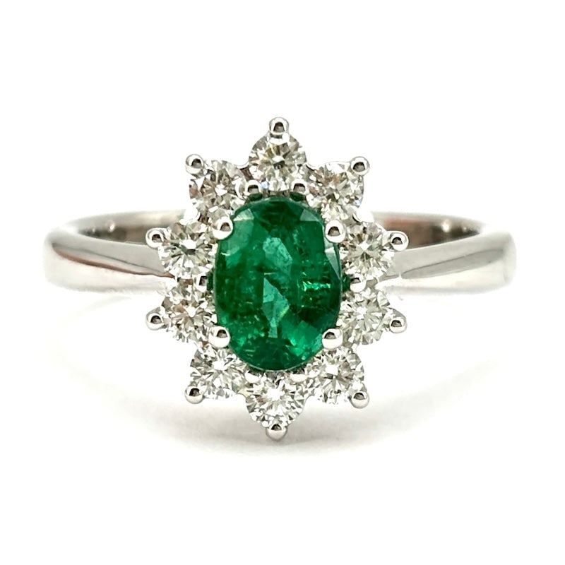 Emerald and diamond daisy ring; 5 gr.: The timeless and regal class of the daisy model ring is offered here in a very refined 18 kt white gold jewel, with precious stunning emerald center surrounded by bright brilliants. Superlative evergr