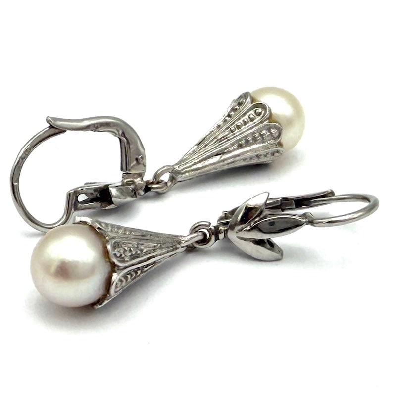 Vintage pearl and gold dangle earrings; 6.09 gr - 3.5 cm: Nivei, romantic style dangle earrings in white gold, with Akoya pearls, embellished with worked bell caps and shamrocks. Closed nun like back for an irresistible touch of retro class for the face, off