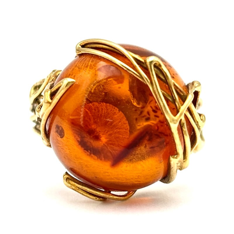 Amber and yellow gold ring; 4.61 gr.: Vintage yellow gold ring with circular button cabochon, a symbol of sunshine and warmth. The setting features branching details that enhance the handcrafted design and beauty of one of the world's mos
