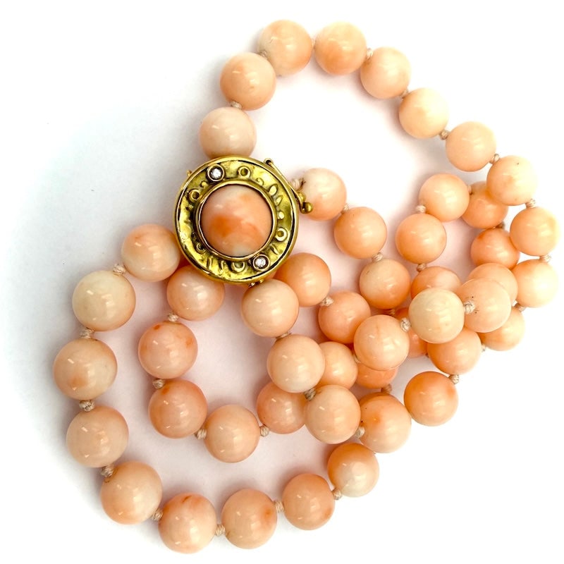 Pink coral ball necklace and vintage gold clasp; 50 cm - 55.2 gr.: One-strand necklace of natural pink coral, spherical, imperfect, with 18 kt yellow gold circular patch clasp, micro rhinestones and coral cabochons. Retro femininity and extraordinary optical effect a