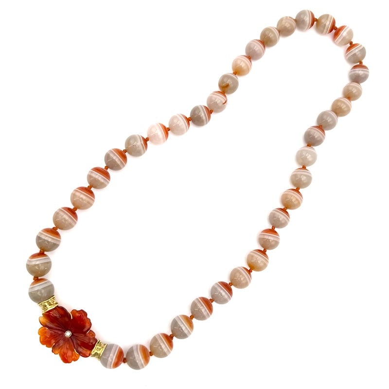 Agate, carnelian flower and gold necklace; 140.8 gr, 56 cm: Very unusual necklace of striated carnelian agate, with sculptural carnelian flower centerpiece with central glitter and important 18 kt yellow gold caps. A piece of jewelry that combines ethnochic st