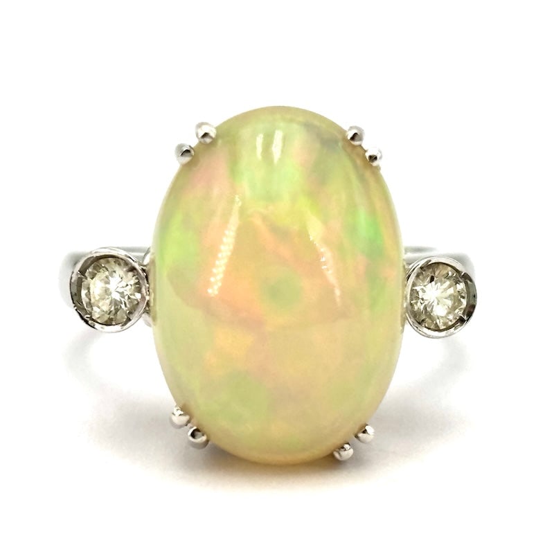 Opal, diamond and gold ring; 7.55 gr.: A fairy-tale oval cabochon of the most opalescent gemstone in the mineral world is the star of this sophisticated and essential piece of jewelry! Iridescent opal ring, romantically enriched with two s
