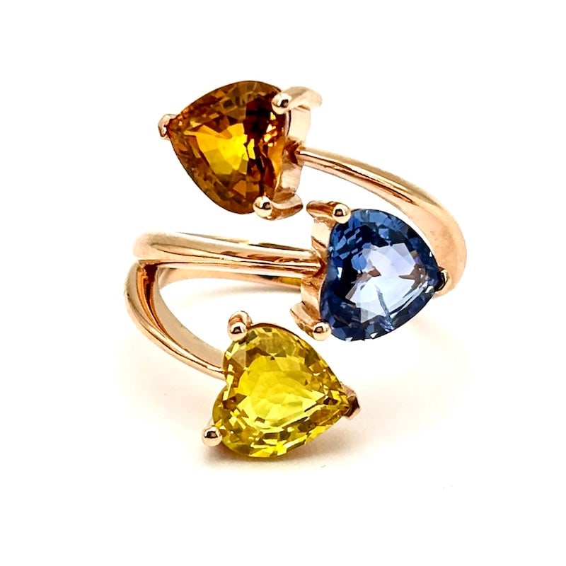 Contrarie ring multi-color sapphire hearts, rose gold; 7.79 gr.: A fairy tale of style! Contrarie ring in 18 kt rose gold with triple crazy heart of multi-colored sapphires. The wrap-around design and precious heart-cut natural colored gemstones enhance the feminin
