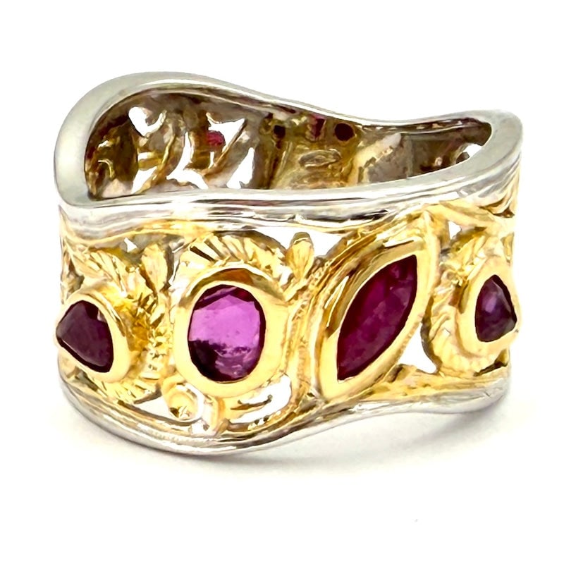 Openwork band ring, rubies and two-tone gold; 7.44 gr.: Enchanting two-tone 18 kt gold pierced band ring with mixed-cut rubies set among intricate fascinating pierced and minutely chiseled motifs. White gold band edges. A ring inspired by the sublime fretw