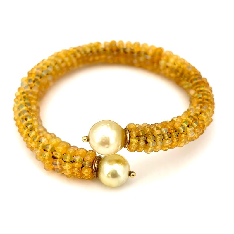 Opal and gold pearls rigid bracelet; 25.85 gr.: Wonderful and unusual rigid bracelet open on the front with natural opals rolled to the silver core and concluding gold sea pearls finished in 18 kt gold. An explosion of sunshine! Our company's certi