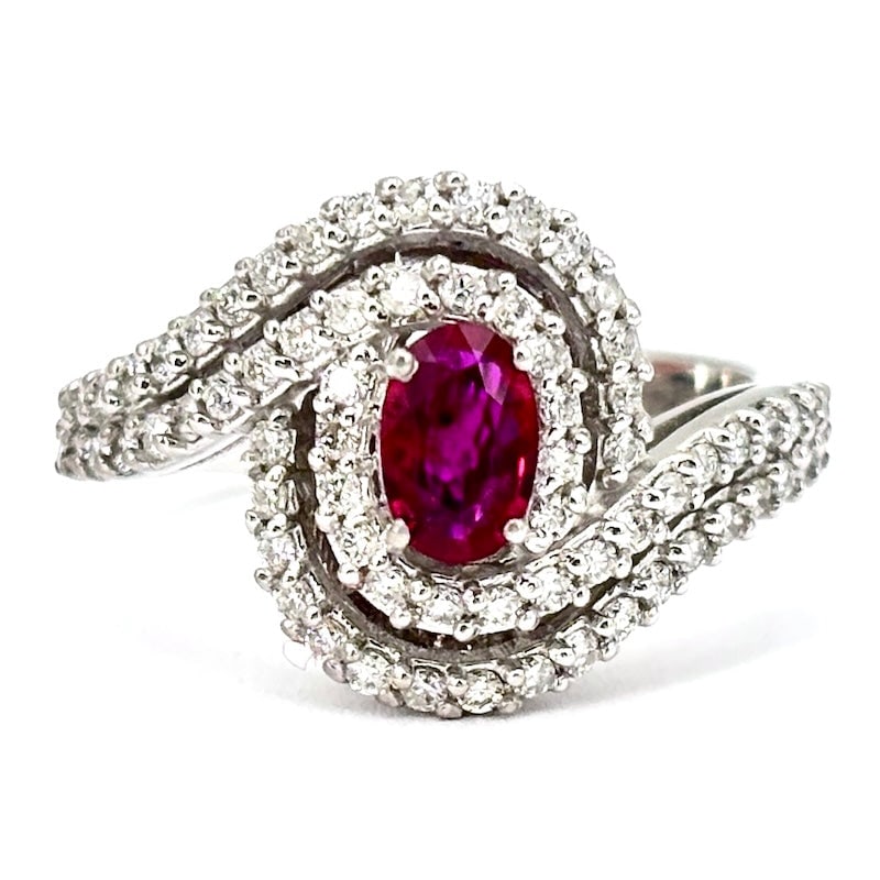 Ruby daisy ring, double round brilliants and gold ; 6.31 gr.: The timeless and regal class of the daisy model ring is offered here in a very refined 18 kt white gold jewel, with a precious central oval-cut ruby surrounded by a very bright sinuous double circle o