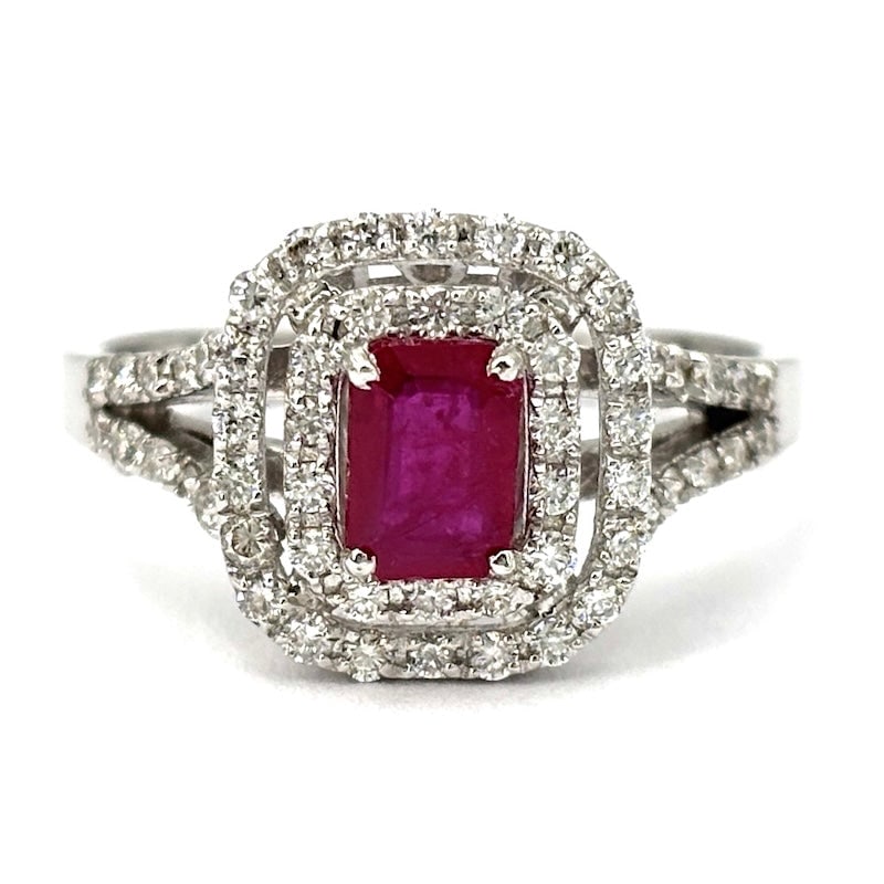 Ruby daisy ring, double round brilliants and gold ; 3.68 gr.: The timeless and regal class of the daisy model ring is offered here in a very refined 18 kt white gold jewel, with a precious emerald-cut ruby center surrounded by a very bright double circle of bril