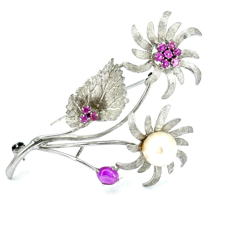 White gold, pearl and ruby double flower brooch; 9.70 gr.: Elegant white gold artistic brooch with a double floral design, with a central pearl on one side radiating sophistication and rubies on the other adding a touch of vibrant color. Perfect for standing 