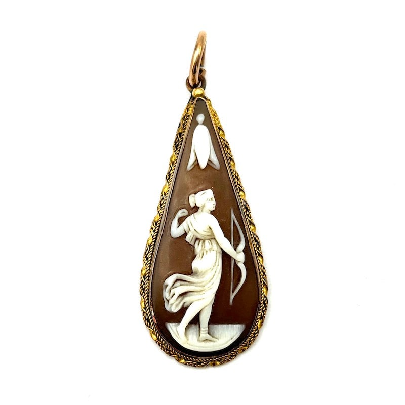 Dame archer and gold cameo pendant; 3.68 gr.: An antique 18K yellow gold pendant featuring a finely carved shell cameo of a lady archer, framed in an ornate twisted border with a graceful drop design. The composition highlights a bold yet refined
