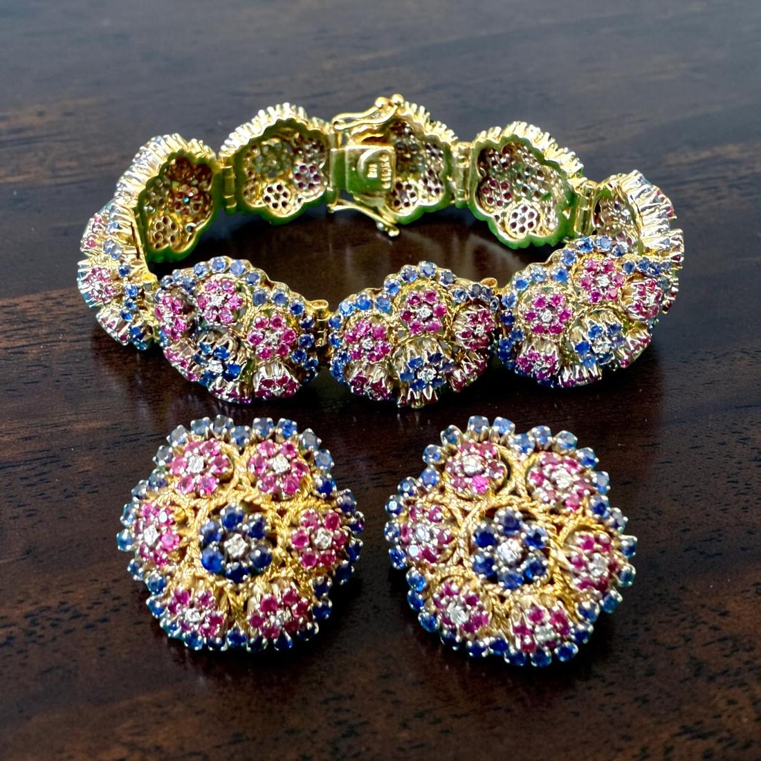 David Webb Gold, Diamond, Ruby and Sapphire Floral Demi-Parure, Signed: A striking and important vintage demi-parure by David Webb, comprising a finely articulated bracelet and a pair of matching ear clips, designed as an elegant floral composition. The set is masterfully