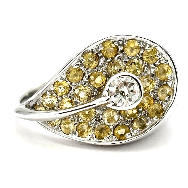 Contrarie calla lily ring in white gold, diamonds and yellow sapphires; 8.7 g: Fabulous calla design ring in 18 kt white gold, with a central solitaire diamond, resting on a maxi petal saddled with yellow sapphires! A truly unique and special piece, a great bargain! Our com